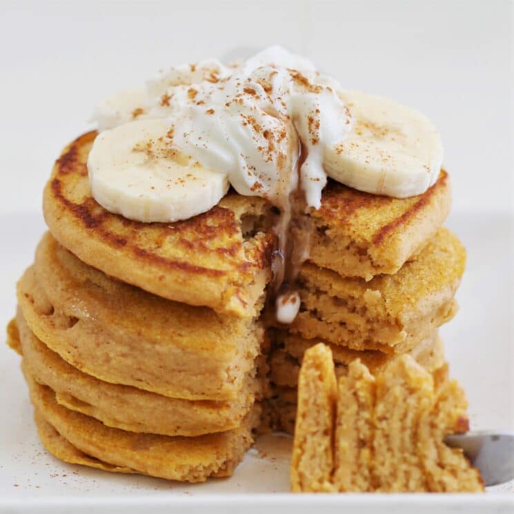 stack of sweet potato pancakes with bananas and whip cream with cinnamon on top